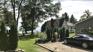 A house with a driveway, a parked car, and a lawn with trees and a view of the water. - Truly a slice of heaven a must see! (Innisfil)