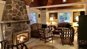 A cozy living room with a stone fireplace, wooden ceiling, and comfortable seating. - Truly a slice of heaven a must see! (Innisfil)