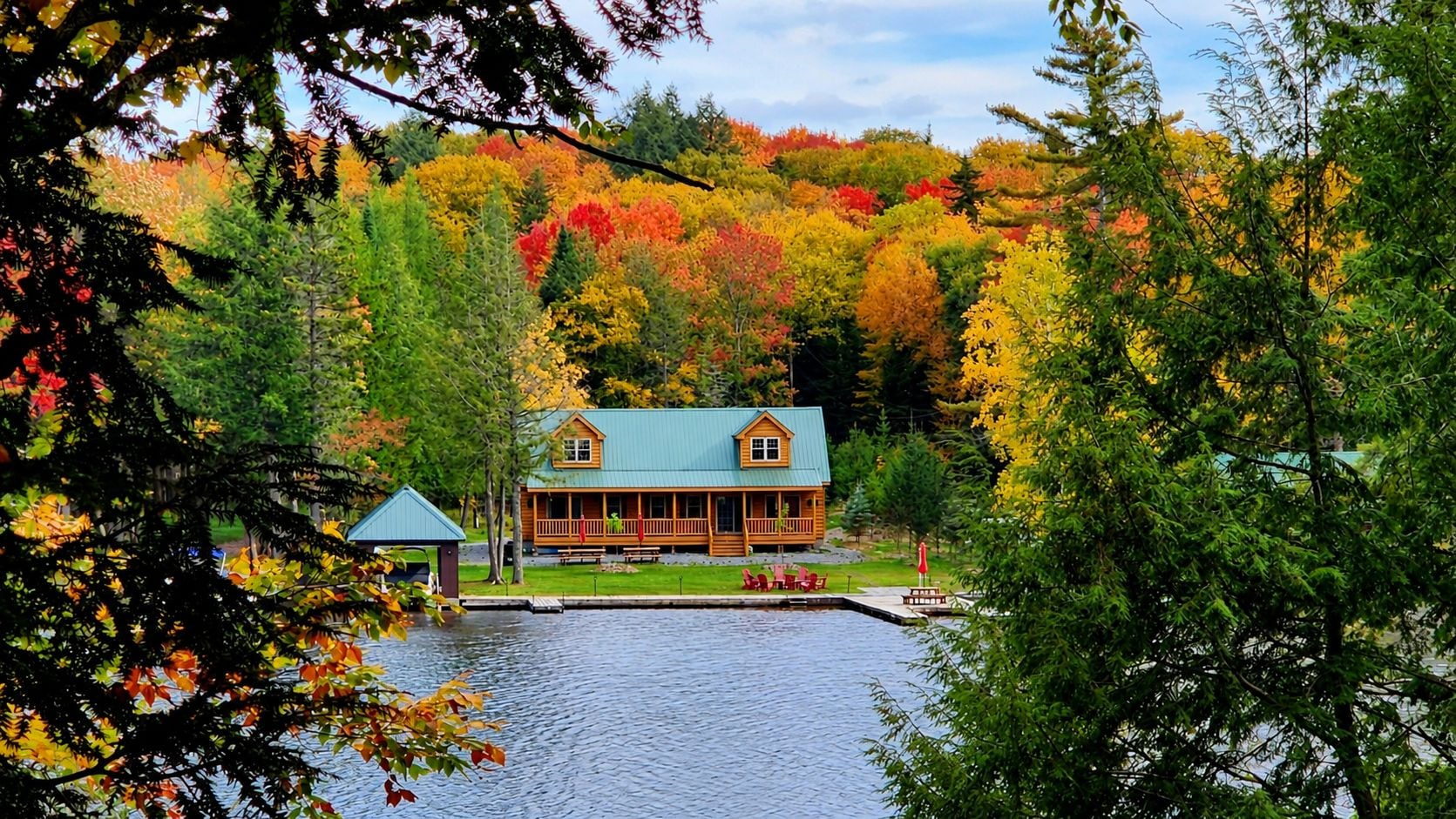 A cabin with a dock, surrounded by autumn foliage.