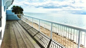 A wooden deck with a white railing overlooking a beach.