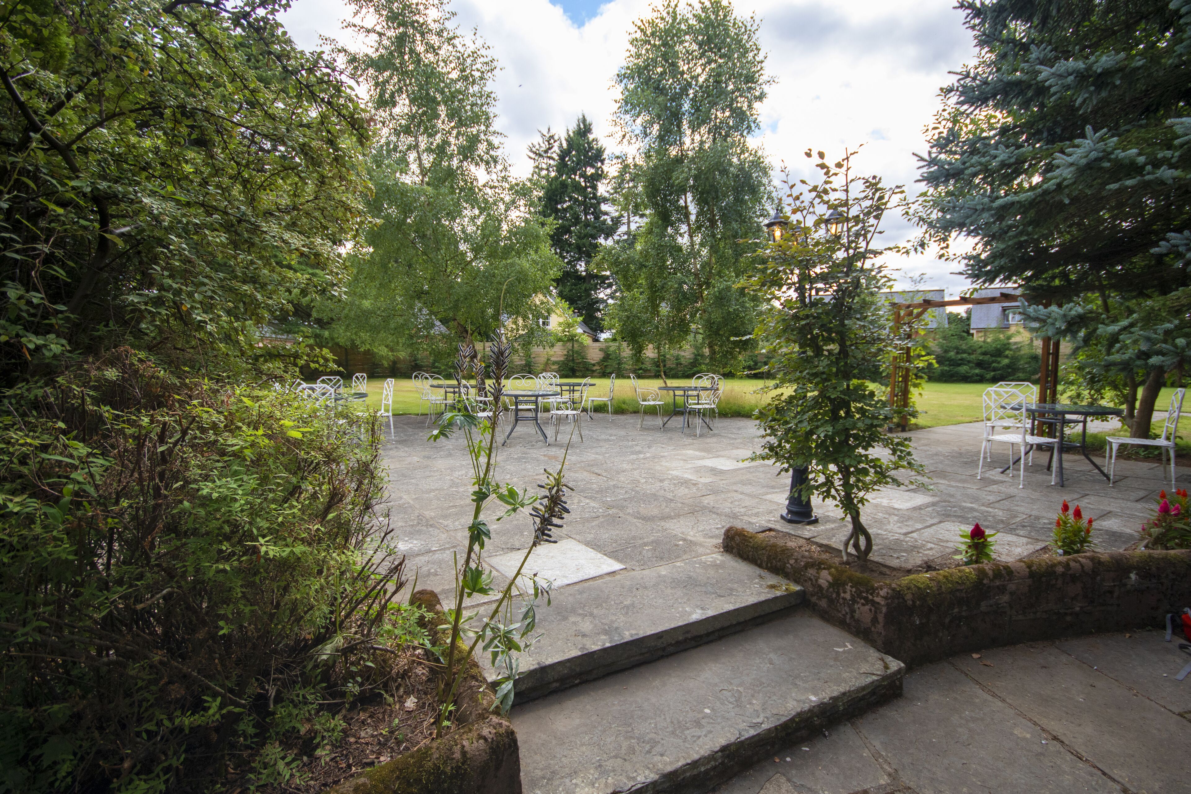 An outdoor patio area with stone flooring, metal chairs, and tables.