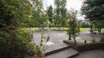 An outdoor patio area with stone flooring, metal chairs, and tables.