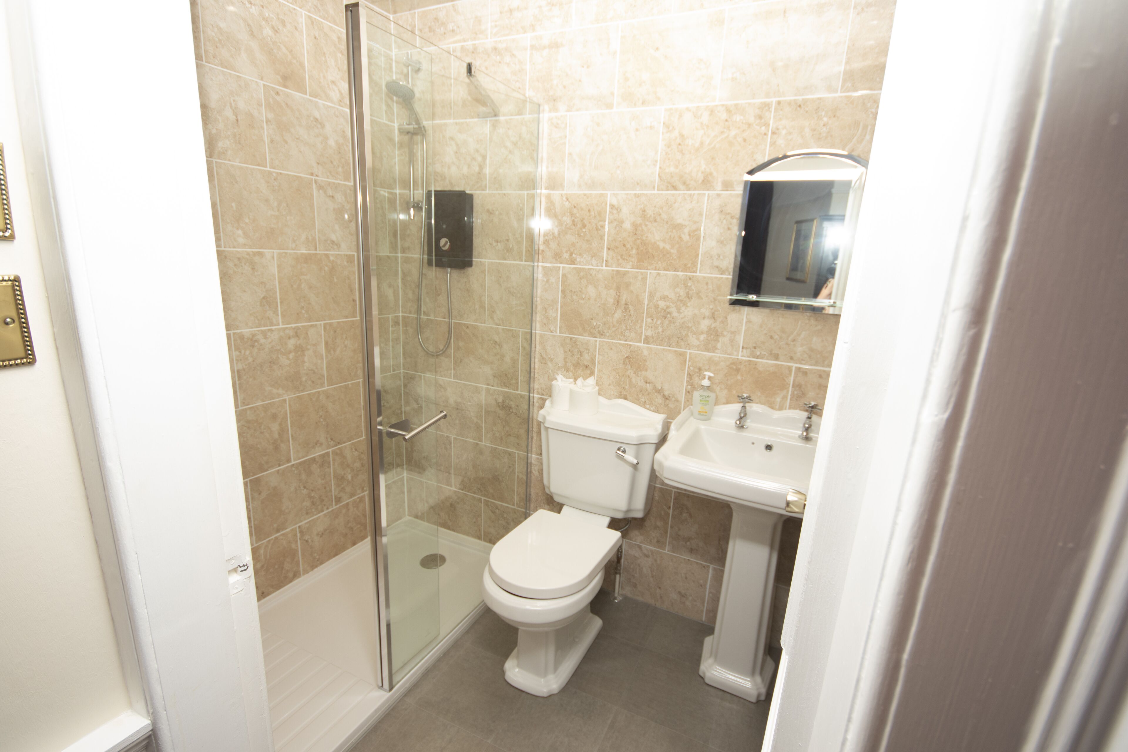 A bathroom with a glass-enclosed shower, a toilet, and a sink.