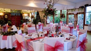 A banquet hall with round tables, white tablecloths, and red sashes.
