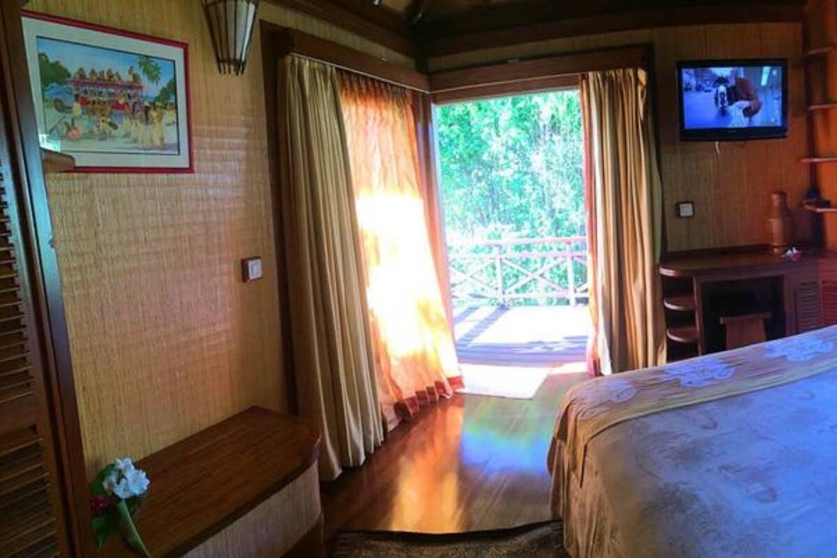 A room with a bed, a television, and a view of the outdoors.