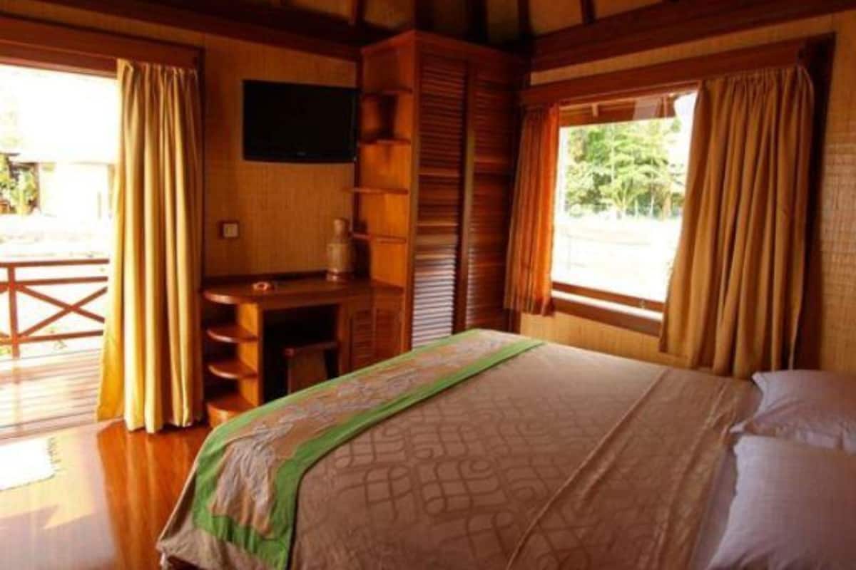 A room with a bed, a desk, and a window with curtains.