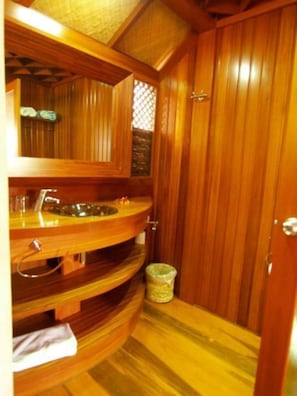A wooden bathroom with a sink, mirror, and a small trash bin. - Fare Vai Nui (Raiatea)