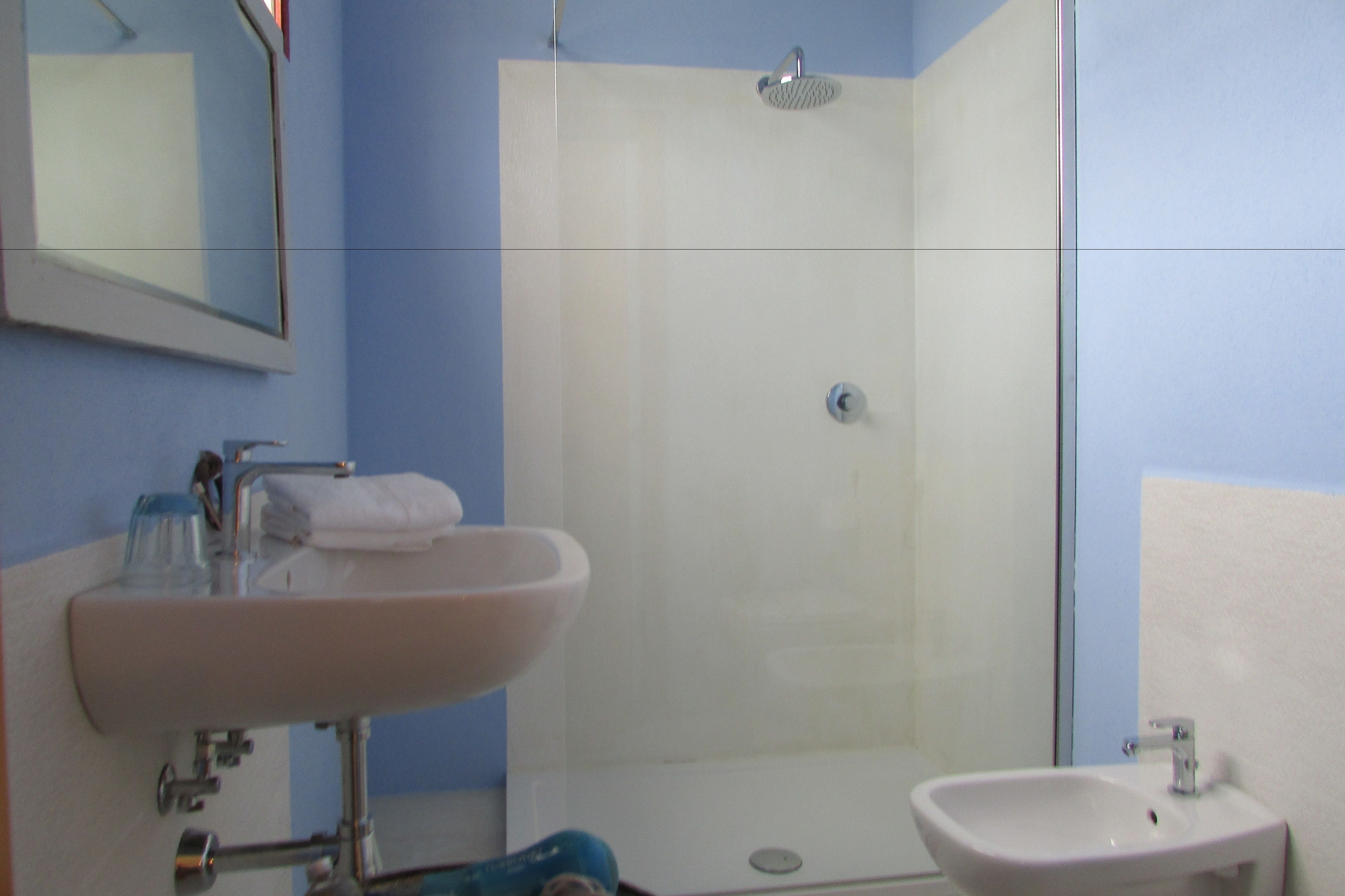 Een badkamer met een wastafel, spiegel en douche.