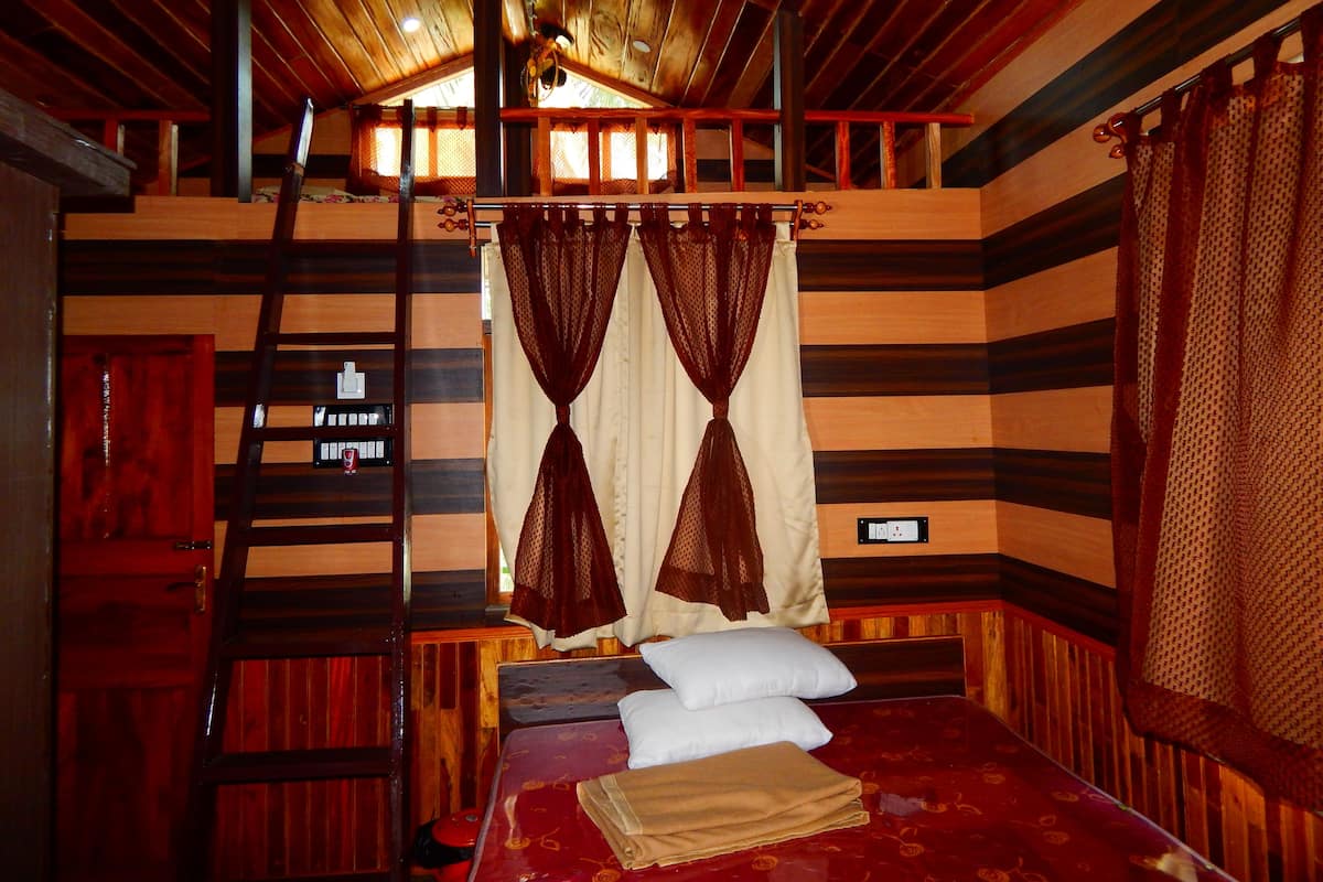 Quarto de cabana de madeira com cama, escada e janela com cortinas.