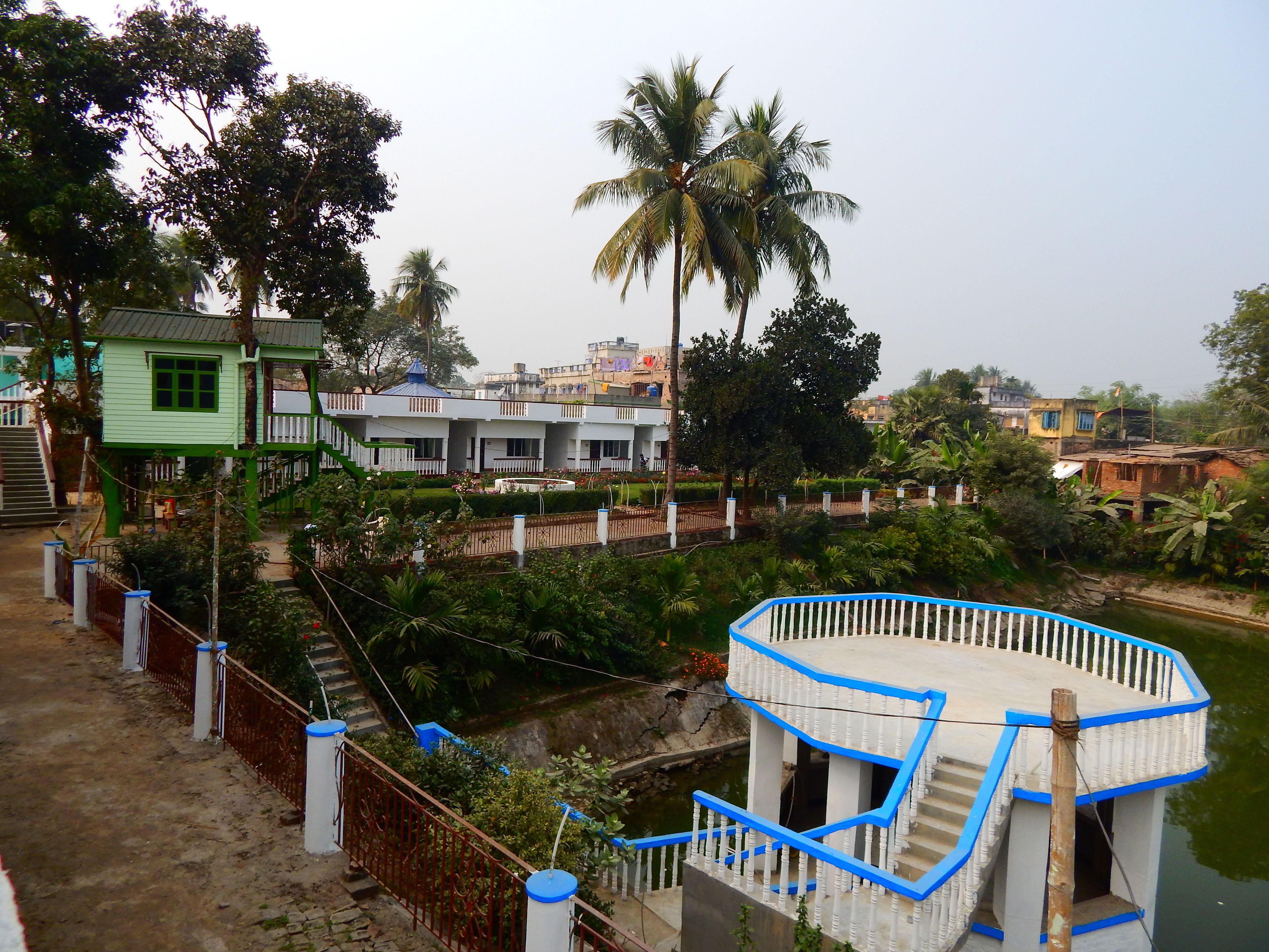 A multi-story building with a blue and white exterior, surrounded by lush greenery and palm trees.