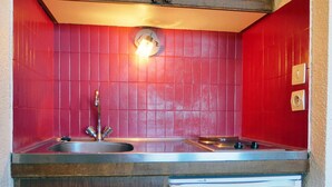 A compact kitchen with a sink, a dishwasher, and a red tiled backsplash. - Quiet studio with balcony, parking and pets allowed (Méribel)