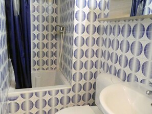 A bathroom with a white sink, a shower with a glass door, and a blue curtain. - Quiet studio with balcony, parking and pets allowed (Méribel)