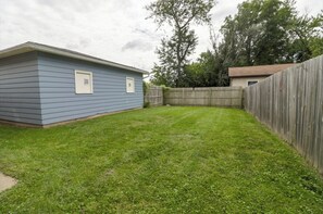 Backyard with a well-maintained lawn and a tree for shade.