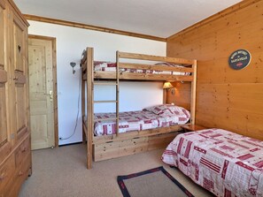 Habitación con literas, una puerta de madera, una lámpara de pared y un letrero que dice 'MOBATAVEL' en la pared.