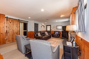 A living room with a sofa, two armchairs, a coffee table, a fireplace, a television, and a wooden sliding door.