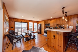 A spacious kitchen with wooden cabinets, a central island, and a dining area with wicker chairs.