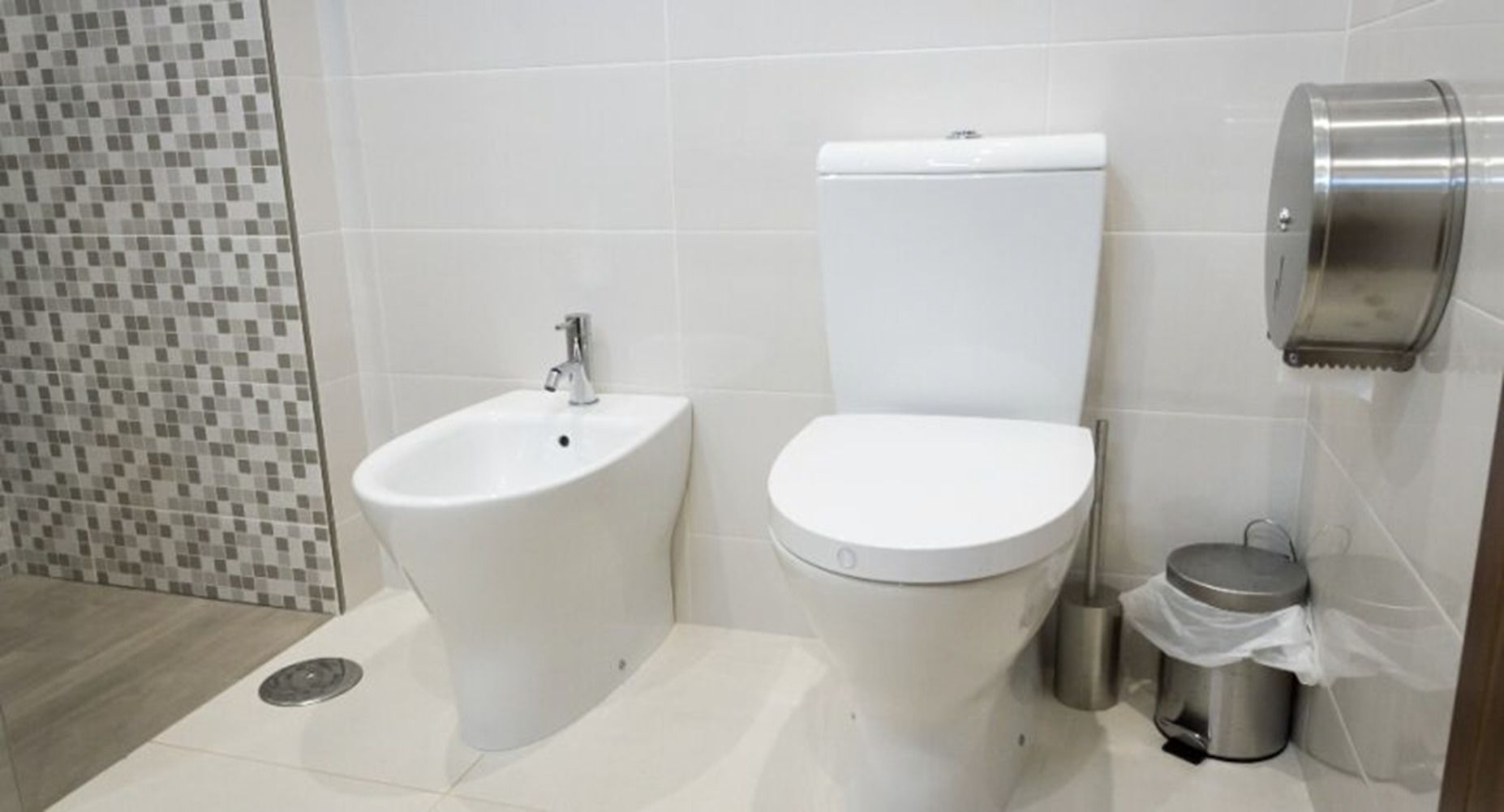 Une salle de bain équipée d’un bidet, de toilettes et d’une poubelle.