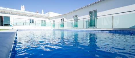 Una piscina al aire libre de temporada, sombrillas