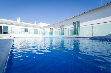 Una piscina al aire libre de temporada, sombrillas