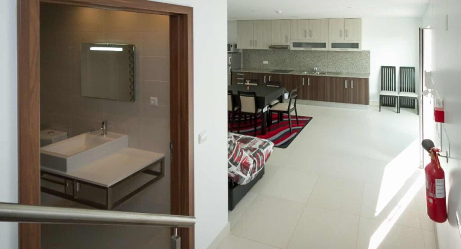 A modern kitchen with dark cabinets, a white countertop, and a red rug.