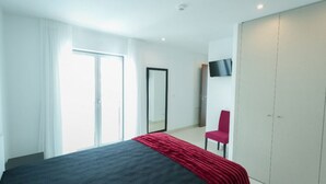 Una moderna camera d'albergo con un ampio letto, una TV a parete e un armadio.