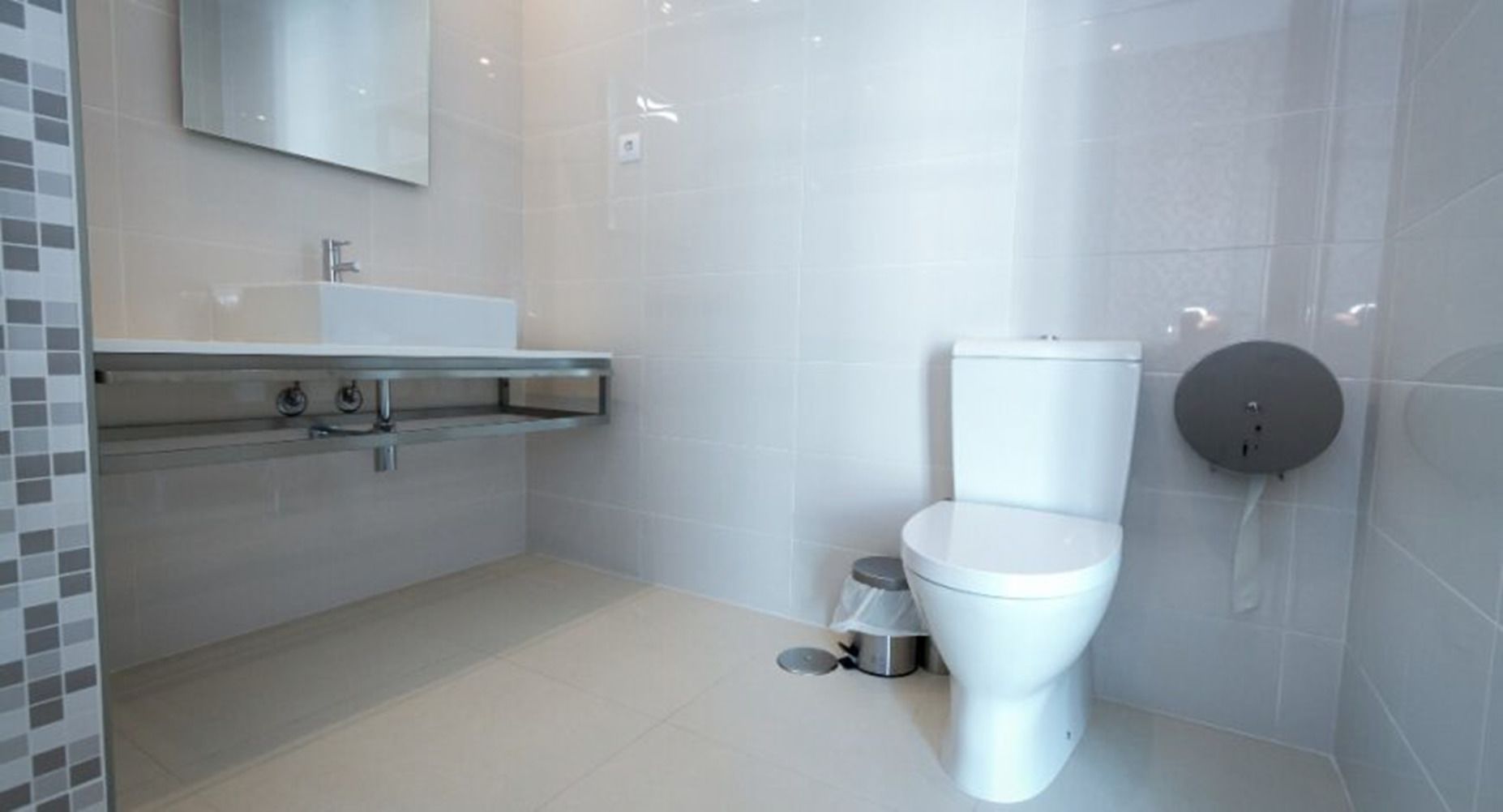 Ein modernes Badezimmer mit Toilette, Waschbecken mit Spiegel und Duschbereich.