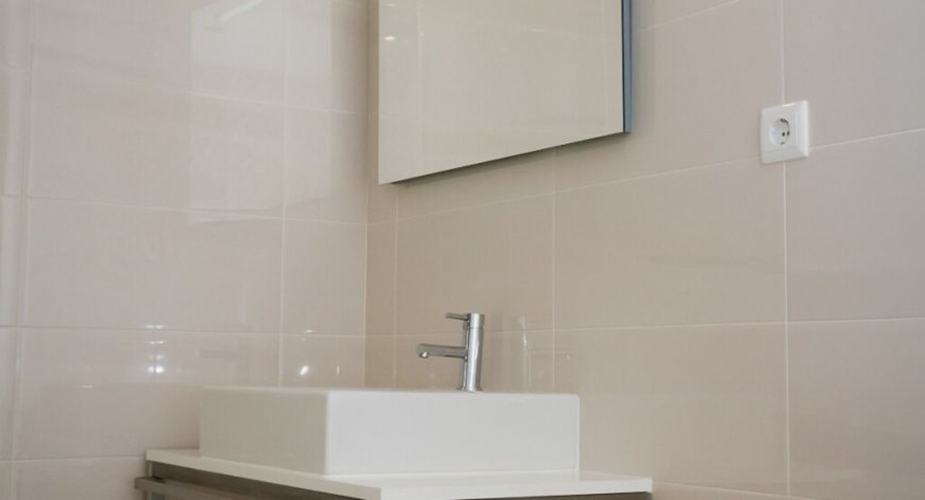 Un baño con un lavabo blanco, un espejo y un interruptor de luz en la pared.