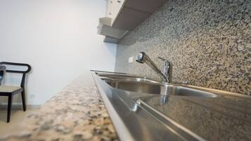 Eine Küche mit Granit-Arbeitsplatten, Edelstahl-Spülen und einem modernen Stuhl.