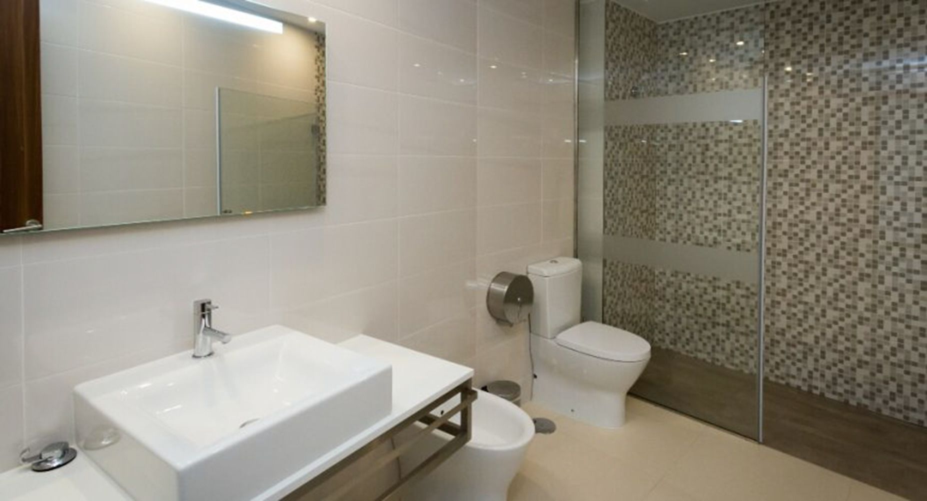 A modern bathroom with a white sink, toilet, and glass shower enclosure.