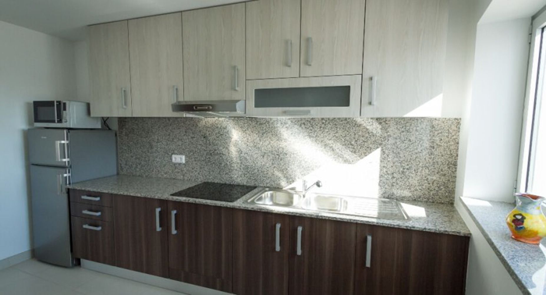 Cucina con piani di lavoro in granito, elettrodomestici in acciaio inossidabile e mobili in legno.