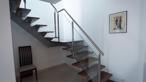 Una moderna scala con ringhiere in vetro e gradini in legno, che conduce a un piano superiore.