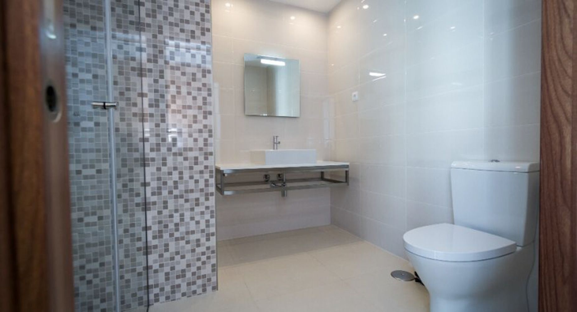 Une salle de bain avec une douche à parois de verre, un lavabo avec un miroir et des toilettes.