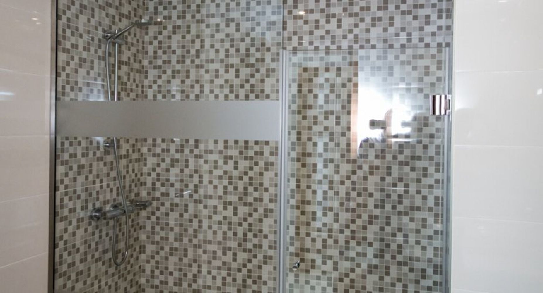 A shower area with tiled walls and a glass door.