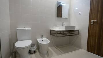 Un bagno moderno con toilette, bidet e lavandino con specchio sopra.