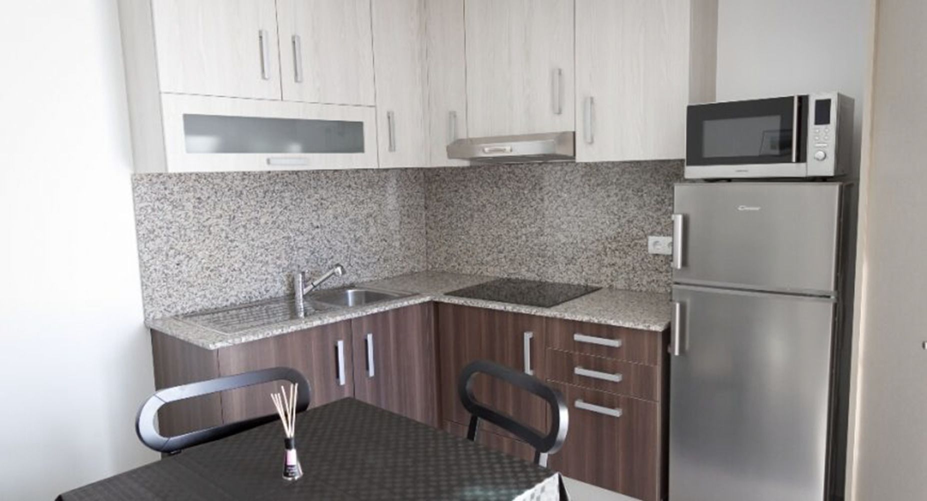A compact kitchen with granite countertops, stainless steel appliances, and wooden cabinets.