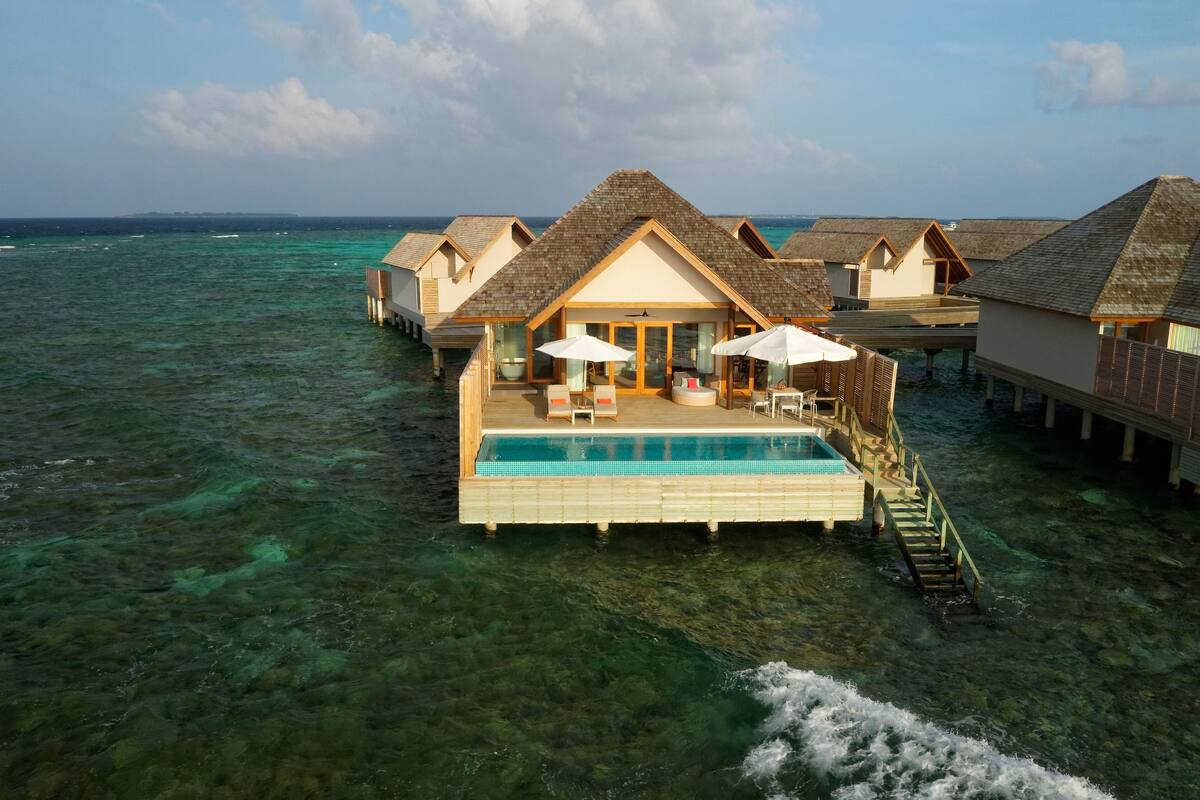 Wasserbungalows mit Schwimmbad, Holzterrasse und Reetdach.