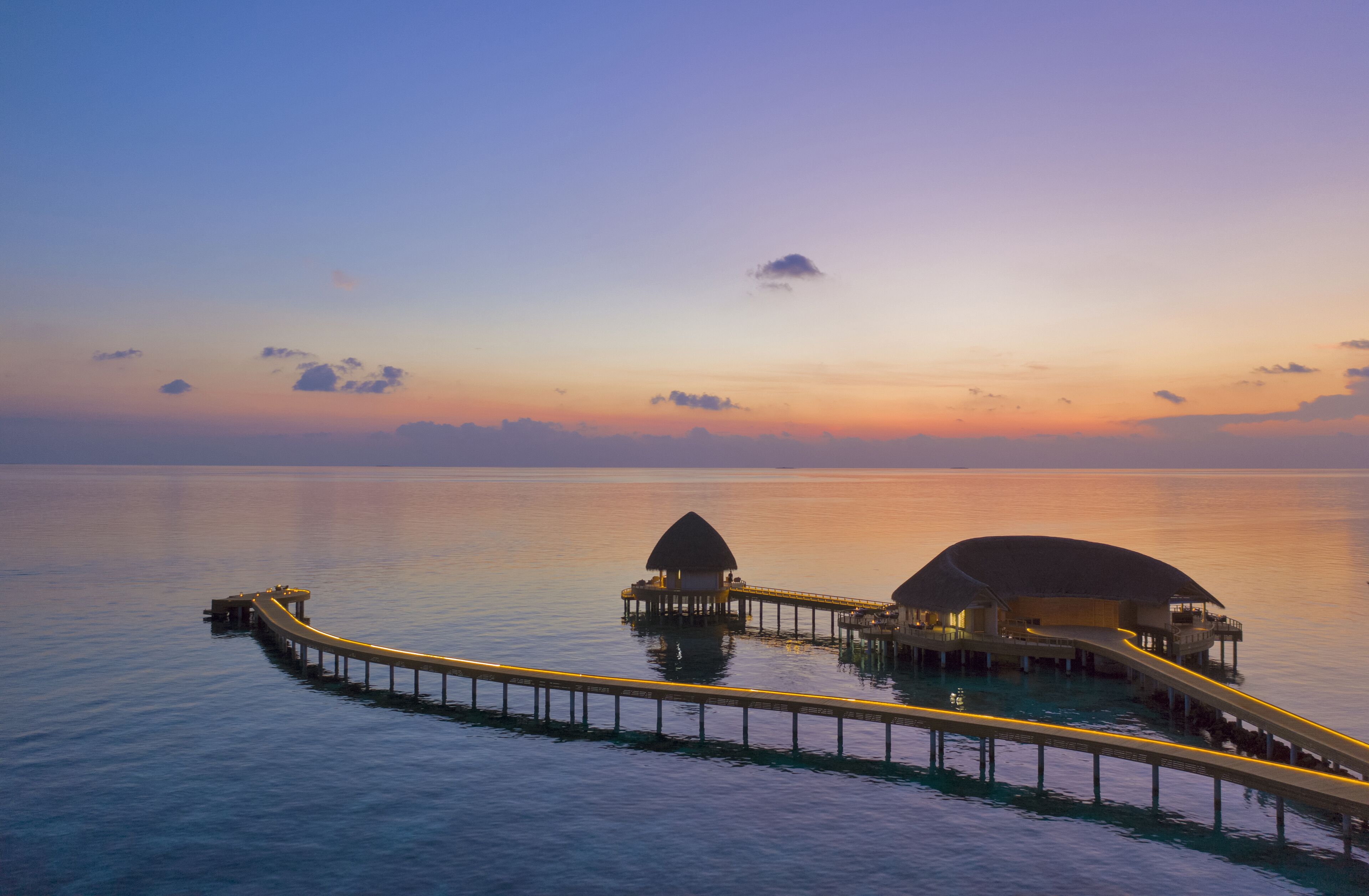 A tranquil overwater resort with a long pier connecting two overwater bungalows.