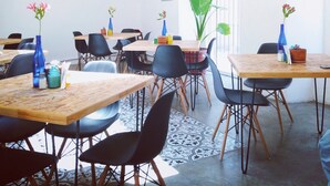 A dining area with tables and chairs, a large plant, and decorative wall art. - Hotel Mamá Carlota (Querétaro)