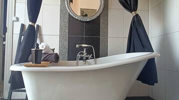 A bathroom with a freestanding bathtub, a mirror, and a towel rack.