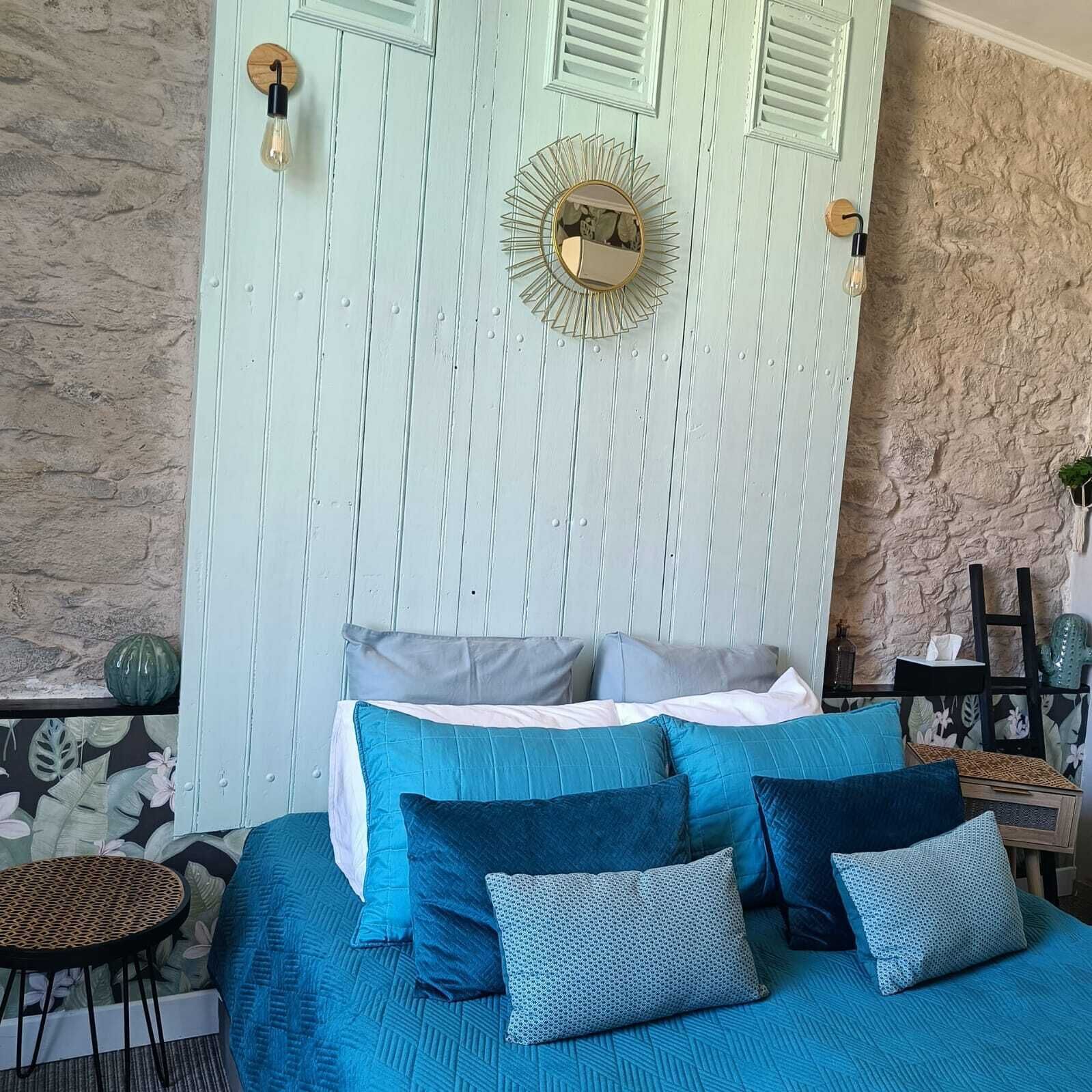 A bedroom with a bed, pillows, a round mirror, and a wall with a textured pattern.