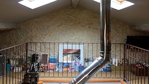 Een kamer met hoge plafonds, een stenen muur, een metalen trap en een dakraam.