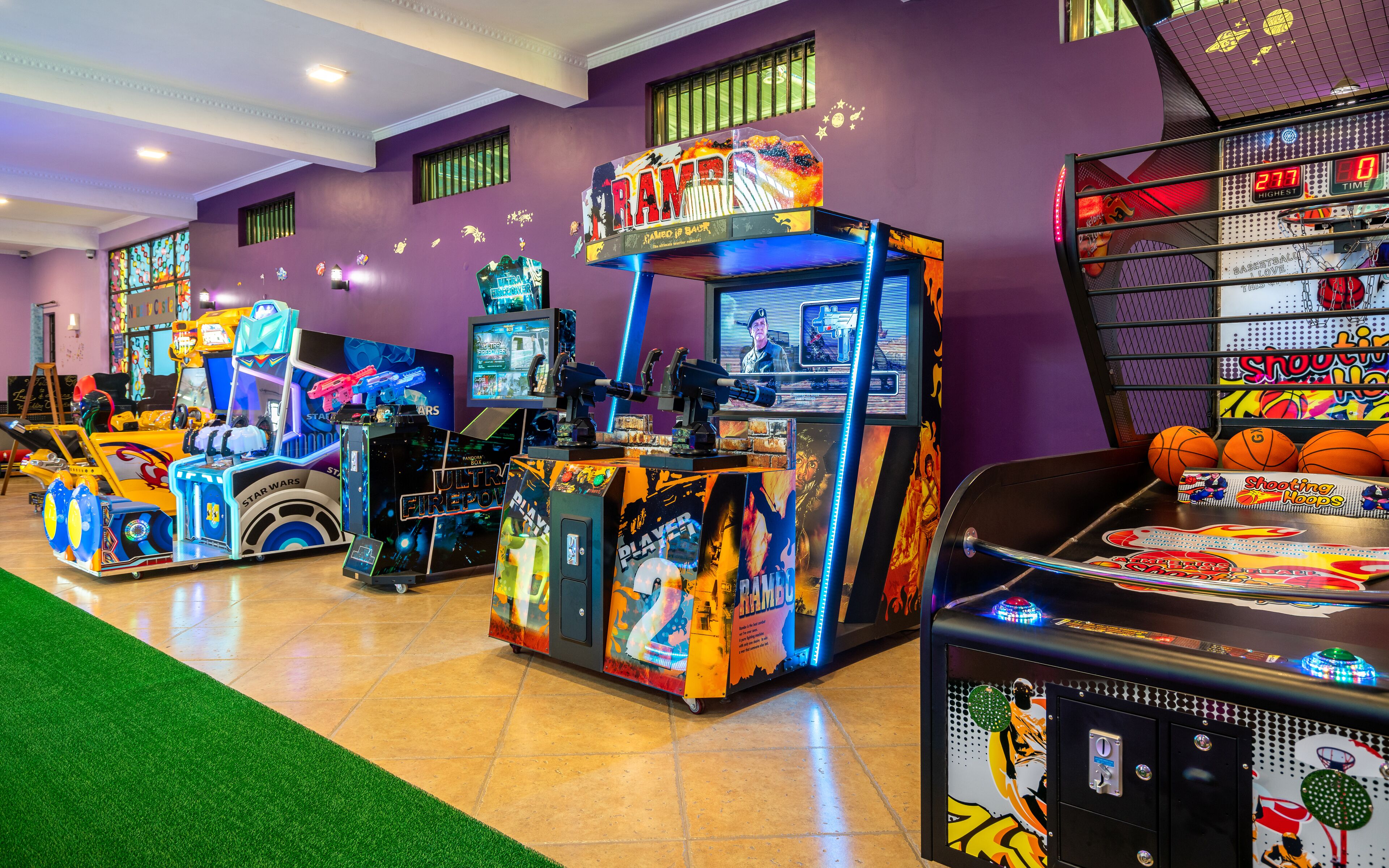 Een speelhal met diverse spelautomaten, waaronder een basketbalspel en een machine met Star Wars thema.