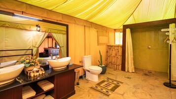A bathroom with a large sink, toilet, and shower area, featuring a wooden interior and a yellow canopy.