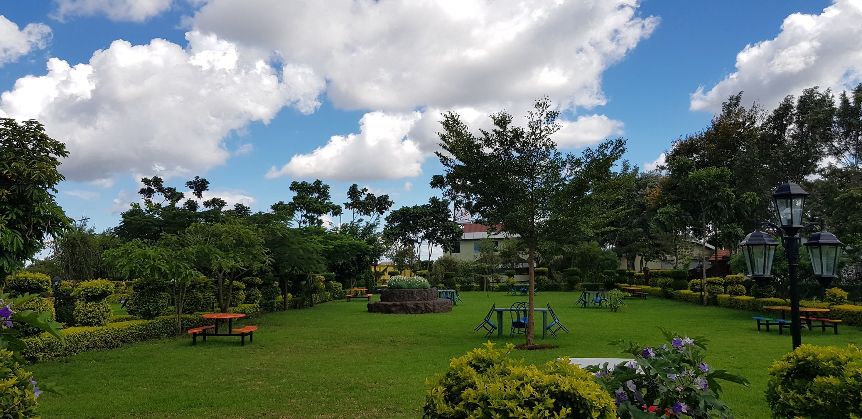 A well-maintained garden with picnic tables, benches, and a swing set.