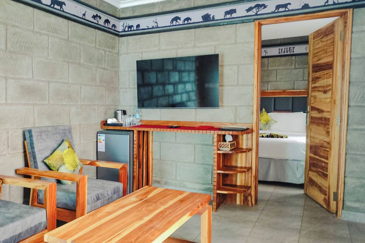 A small, cozy room with a sofa, wooden table, and a small kitchenette.