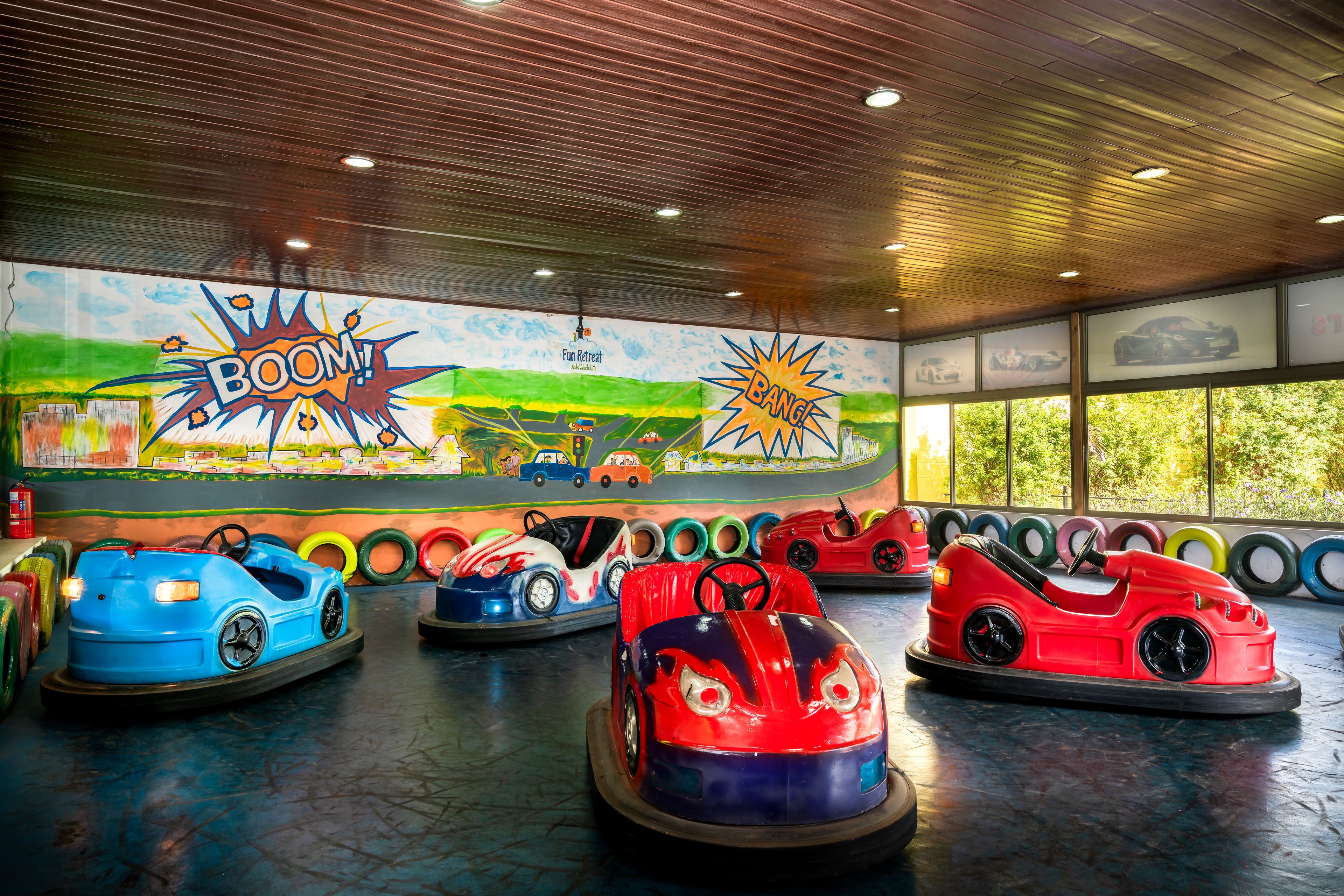 An indoor amusement ride with bumper cars and a mural of cars on the wall.