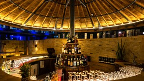 A bar area with a wooden ceiling, a central liquor display, and a circular arrangement of glasses.