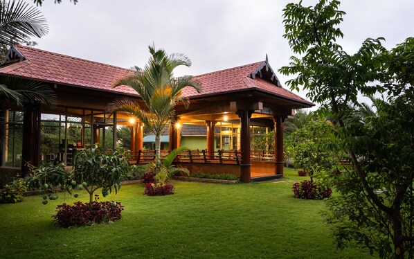A traditional-style building with a red tiled roof, large windows, and a covered outdoor seating area.