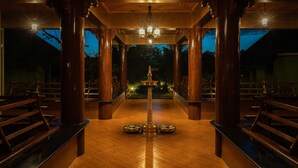 A covered outdoor area with wooden benches and a central decorative structure.