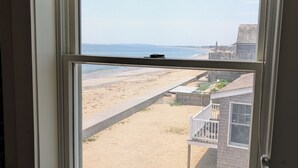 Una ventana con vista a una playa, una estructura de madera y un cielo despejado.